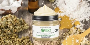 CBD cream jar surrounded by natural ingredients and cannabis buds