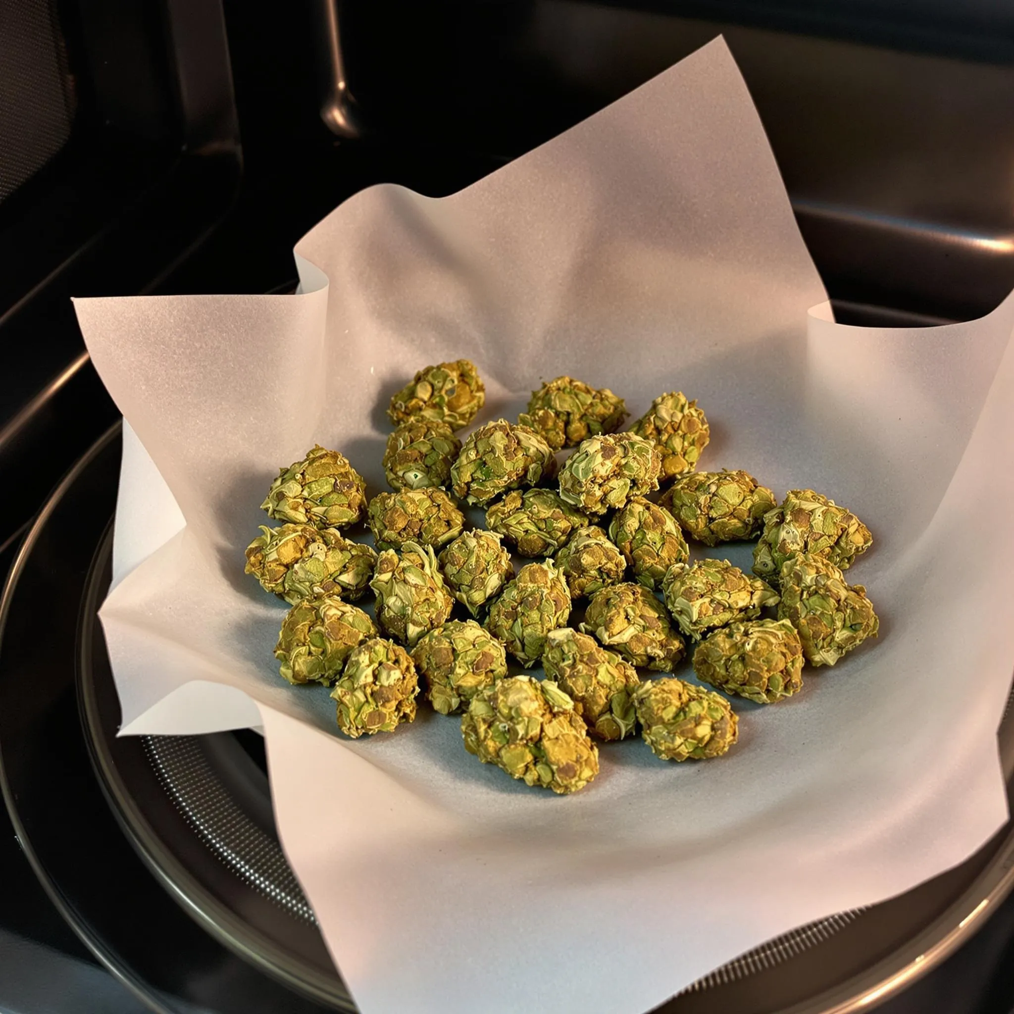 Cannabis buds on a plate inside a microwave prepared for quick drying.