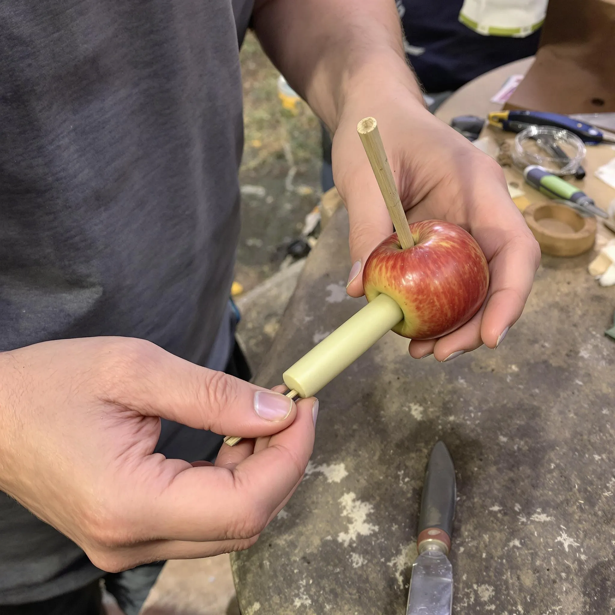 Person making an apple pipe using a skewer and knife for smoking cannabis without a pipe