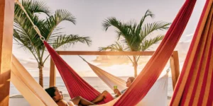 Couples relaxing on colorful hammocks by the beach at a Caribbean resort during sunset