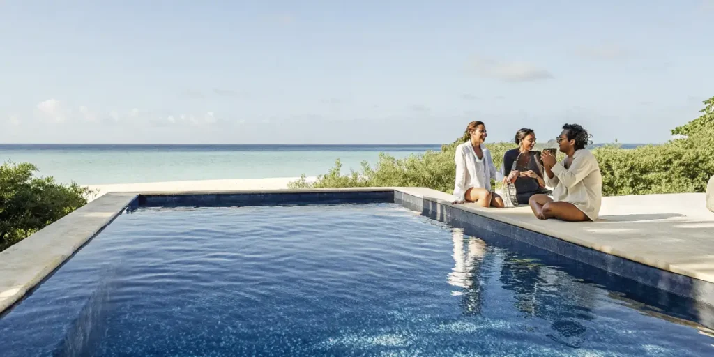 Friends enjoying drinks by an infinity pool overlooking the Caribbean Sea